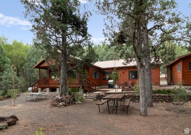 rear view of house featuring a deck, a patio, metal roof, and faux log siding