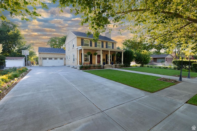 colonial inspired home featuring an outbuilding, driveway, a yard, covered porch, and brick siding