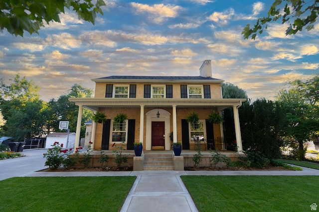 view of front of house with a chimney, a porch, a front yard, and fence