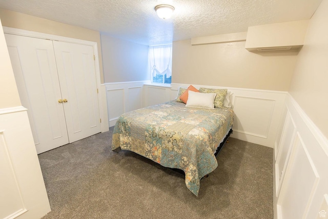 carpeted bedroom featuring a decorative wall, a wainscoted wall, and a textured ceiling