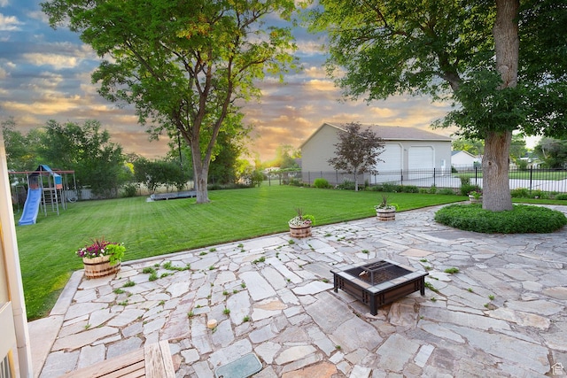 view of patio / terrace with a fire pit, a playground, a garage, and fence