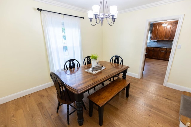 dining space featuring crown molding, light wood-style flooring, baseboards, and a chandelier