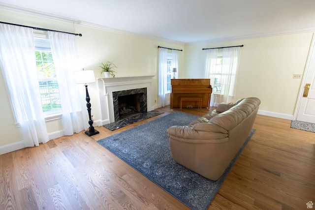 living room featuring wood finished floors, baseboards, a high end fireplace, and ornamental molding