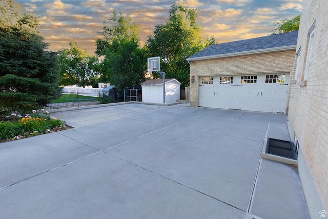 exterior space featuring an outbuilding, a shed, fence, a garage, and brick siding