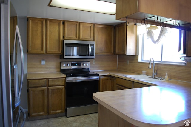 71 Gary Way N, Salt Lake, UT 84054 - kitchen featuring stainless steel appliances, light countertops, a peninsula, decorative backsplash, and brown cabinets