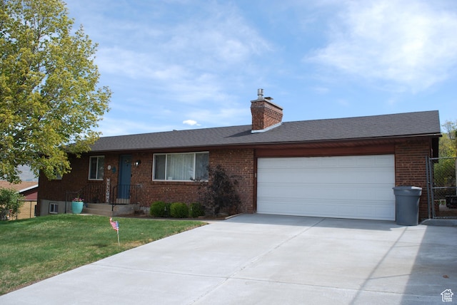 single story home featuring a chimney, brick siding, a garage, a front lawn, and concrete driveway