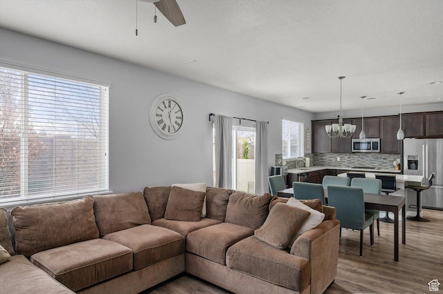 12172 S Window Arch Ln, Herriman, UT 84096 - living area with light wood-type flooring and ceiling fan with notable chandelier