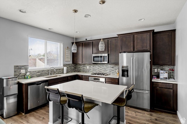 12172 S Window Arch Ln, Herriman, UT 84096 - kitchen with a sink, wood finished floors, dark brown cabinetry, and appliances with stainless steel finishes