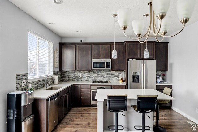 12172 S Window Arch Ln, Herriman, UT 84096 - kitchen featuring backsplash, a kitchen island, a sink, dark brown cabinets, and appliances with stainless steel finishes