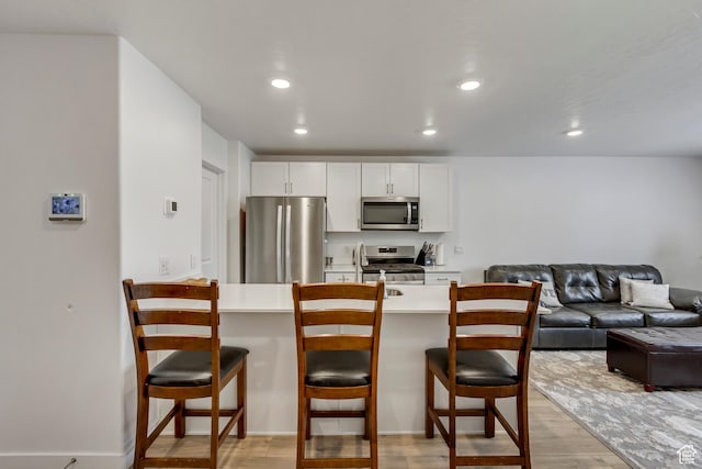 1436 S Divide Dr, Santaquin, UT 84655 - kitchen with stainless steel appliances, a breakfast bar, and light wood-type flooring