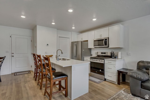 1436 S Divide Dr, Santaquin, UT 84655 - kitchen with a sink, light wood finished floors, a kitchen breakfast bar, stainless steel appliances, and white cabinets