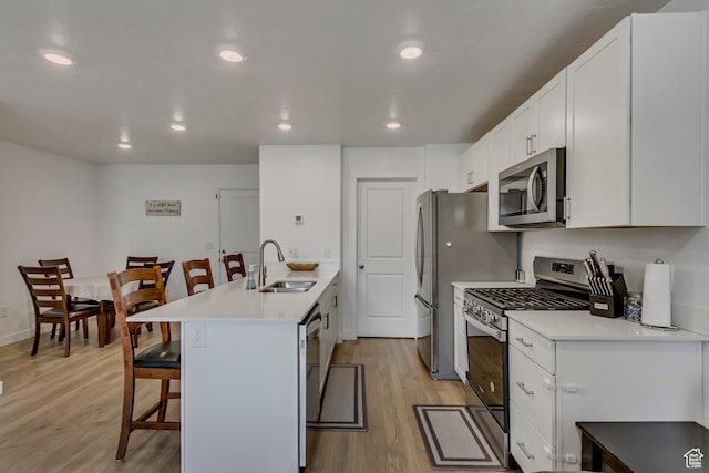 1436 S Divide Dr, Santaquin, UT 84655 - kitchen featuring a kitchen breakfast bar, a sink, light wood-style flooring, a peninsula, and appliances with stainless steel finishes