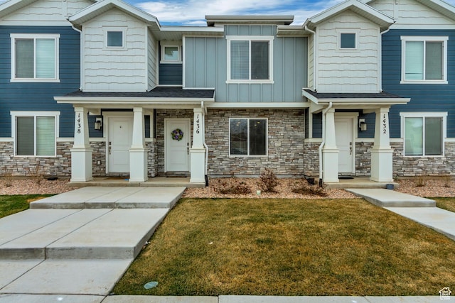 view of front of home with a front lawn, stone siding, and board and batten siding
