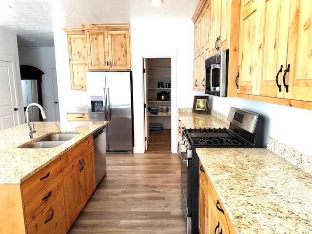 352 W Ropelato Dr, Nibley, UT 84321 - kitchen featuring stainless steel appliances, a sink, wood finished floors, light stone countertops, and a kitchen island with sink