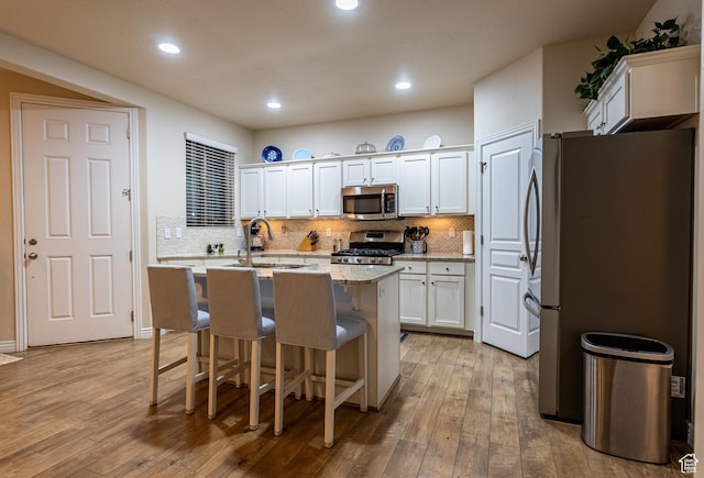 160 S 2775 W, West Point, UT 84015 - kitchen featuring a kitchen island with sink, a sink, stainless steel appliances, white cabinets, and light wood-type flooring