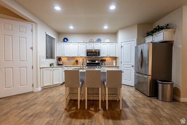 160 S 2775 W, West Point, UT 84015 - kitchen featuring white cabinets, appliances with stainless steel finishes, light wood-type flooring, and a kitchen island with sink