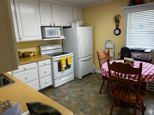 kitchen with stone finish flooring, light countertops, ornamental molding, white cabinets, and white appliances