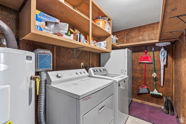 laundry area with electric water heater, laundry area, washer and dryer, and wood walls