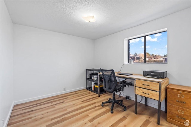 office space with baseboards, light wood-type flooring, and a textured ceiling