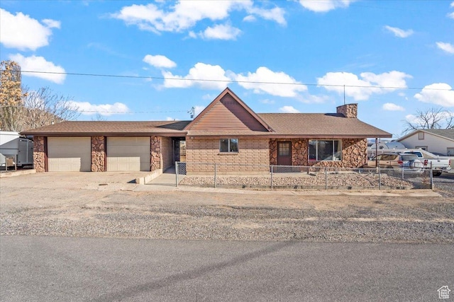 ranch-style home with stone siding, aphalt driveway, an attached garage, a chimney, and a fenced front yard