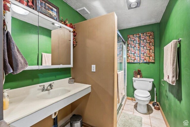 bathroom featuring visible vents, a shower stall, toilet, tile patterned floors, and a sink