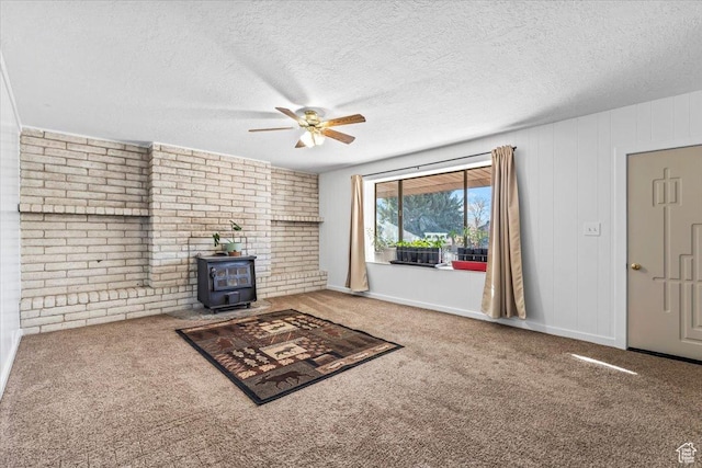 unfurnished living room with a textured ceiling, a wood stove, carpet flooring, and a ceiling fan
