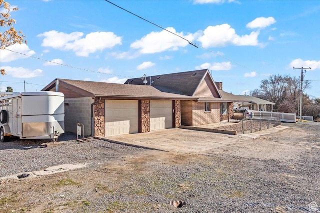 exterior space with driveway, stone siding, a garage, and a chimney
