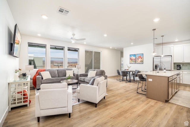 living area featuring visible vents, baseboards, recessed lighting, light wood-style flooring, and a ceiling fan