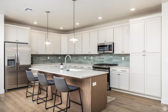 757 W Periwinkle Ln Unit 210, St George, UT 84790 - kitchen featuring appliances with stainless steel finishes, a sink, light wood-style flooring, a kitchen island with sink, and light countertops