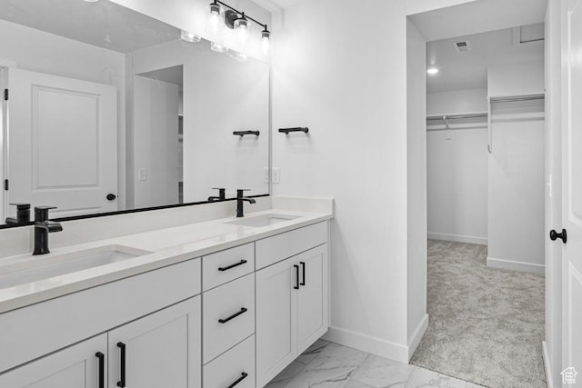 full bath with a walk in closet, marble finish floor, baseboards, and a sink