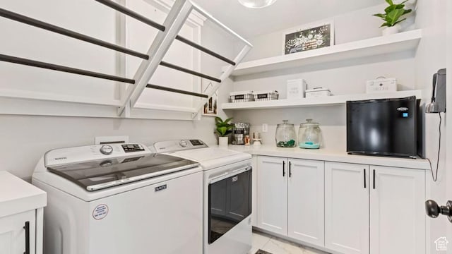 washroom featuring marble finish floor, washer and clothes dryer, and cabinet space