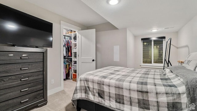 bedroom with a closet, a spacious closet, baseboards, light colored carpet, and visible vents