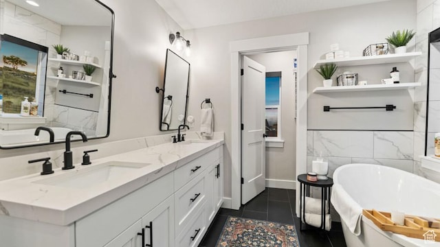 bathroom with double vanity, a sink, a freestanding tub, and tile patterned floors