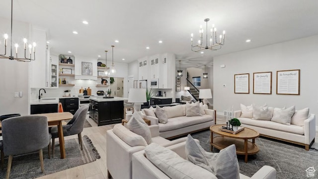 living room featuring light wood finished floors, stairway, a chandelier, and recessed lighting