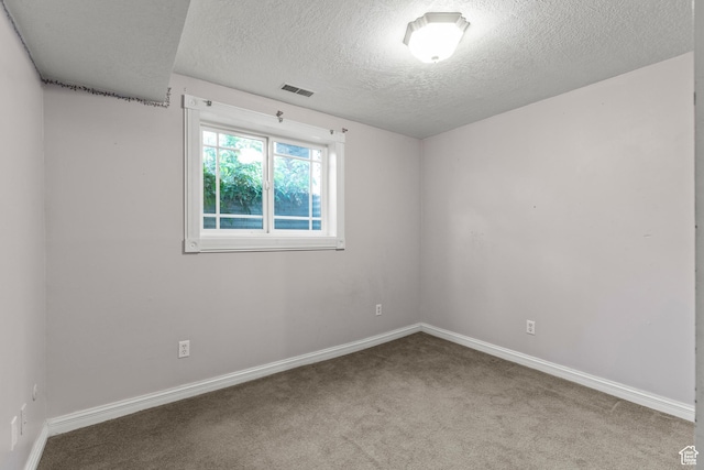 empty room with baseboards, carpet, a textured ceiling, and visible vents