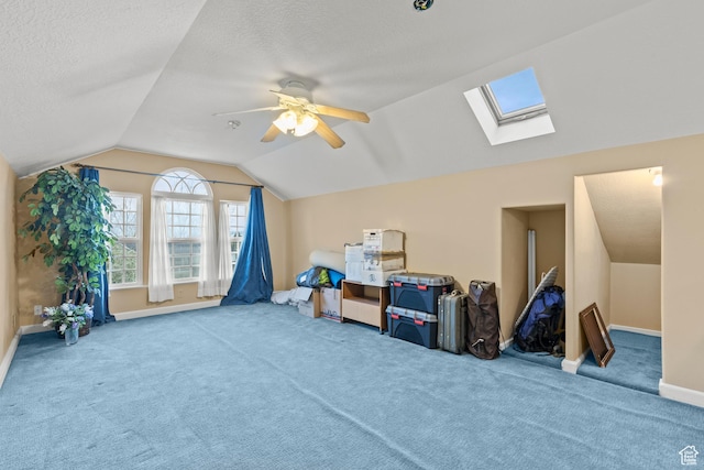 additional living space with ceiling fan, a textured ceiling, carpet floors, baseboards, and lofted ceiling with skylight