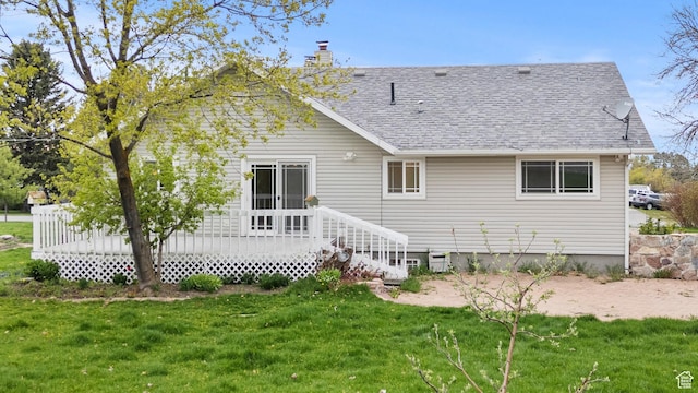back of property featuring a lawn, a wooden deck, a chimney, and a shingled roof