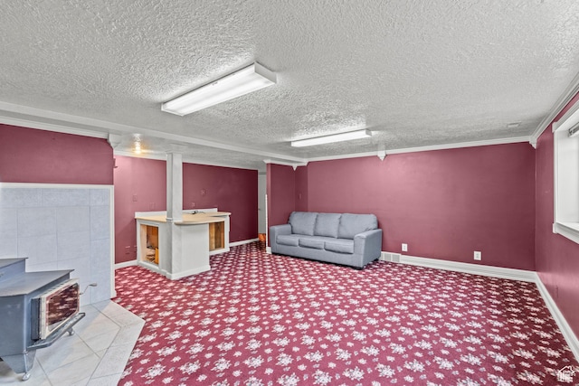 finished below grade area featuring visible vents, a wood stove, carpet floors, baseboards, and a textured ceiling
