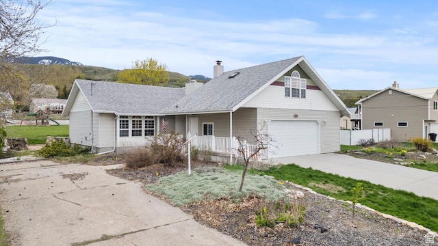 traditional home featuring a garage, fence, roof with shingles, a chimney, and concrete driveway