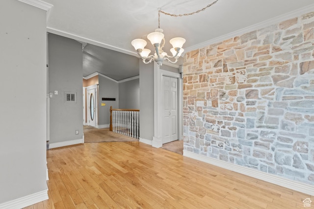 unfurnished dining area with an inviting chandelier, baseboards, ornamental molding, and wood finished floors