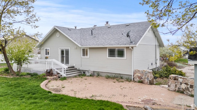 rear view of property featuring a shingled roof, a yard, a deck, and a chimney
