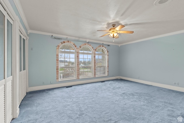 spare room with carpet floors, ceiling fan, crown molding, and baseboards