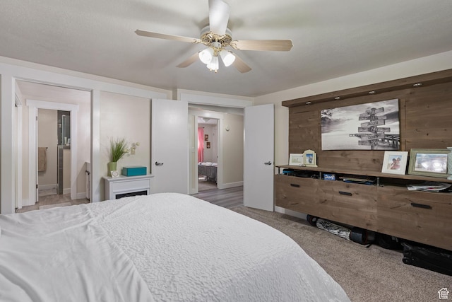 carpeted bedroom featuring connected bathroom, ceiling fan, and wooden walls