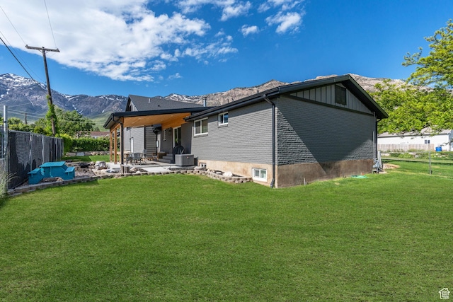 back of property featuring a patio area, cooling unit, fence, a lawn, and a mountain view