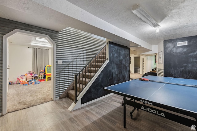 recreation room featuring visible vents, wood finished floors, and a textured ceiling