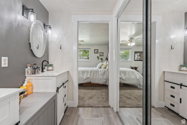 full bath with vanity, wood finished floors, ceiling fan, and ensuite bathroom