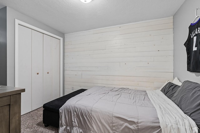 bedroom with a closet, wood walls, carpet floors, and a textured ceiling