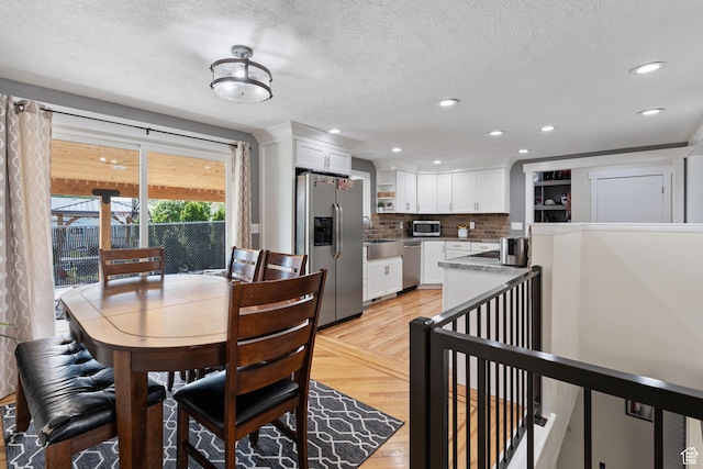 dining area featuring light wood-style flooring, recessed lighting, and a textured ceiling
