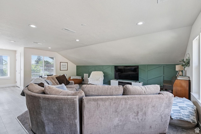 living room featuring baseboards, lofted ceiling, visible vents, and recessed lighting