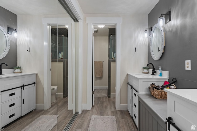 bathroom with baseboards, toilet, wood finished floors, and a sink